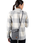 Woman wearing a plaid shirt with a gray crossbody bag on a white background
