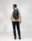 Person wearing a navy backpack on a plain background
