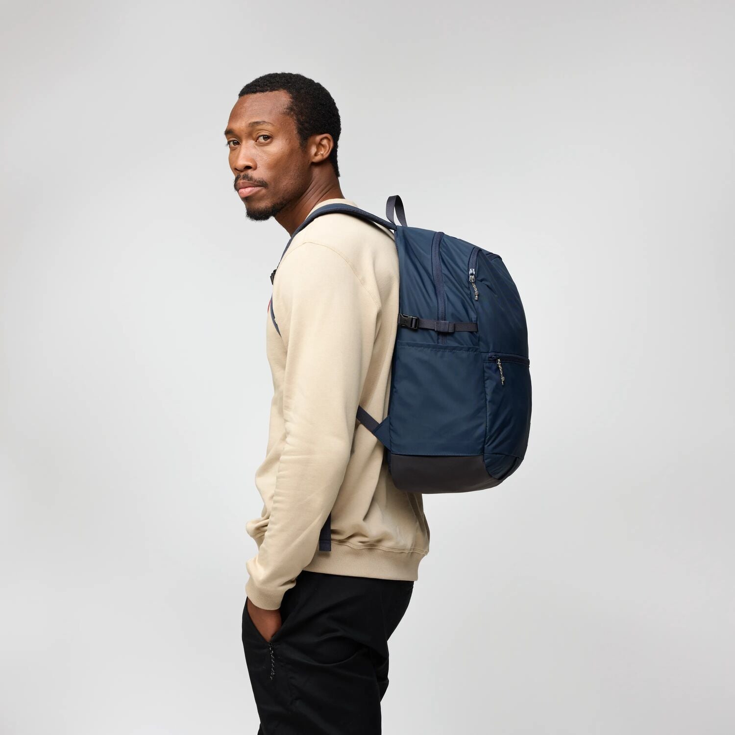 Man wearing a blue backpack on a plain background