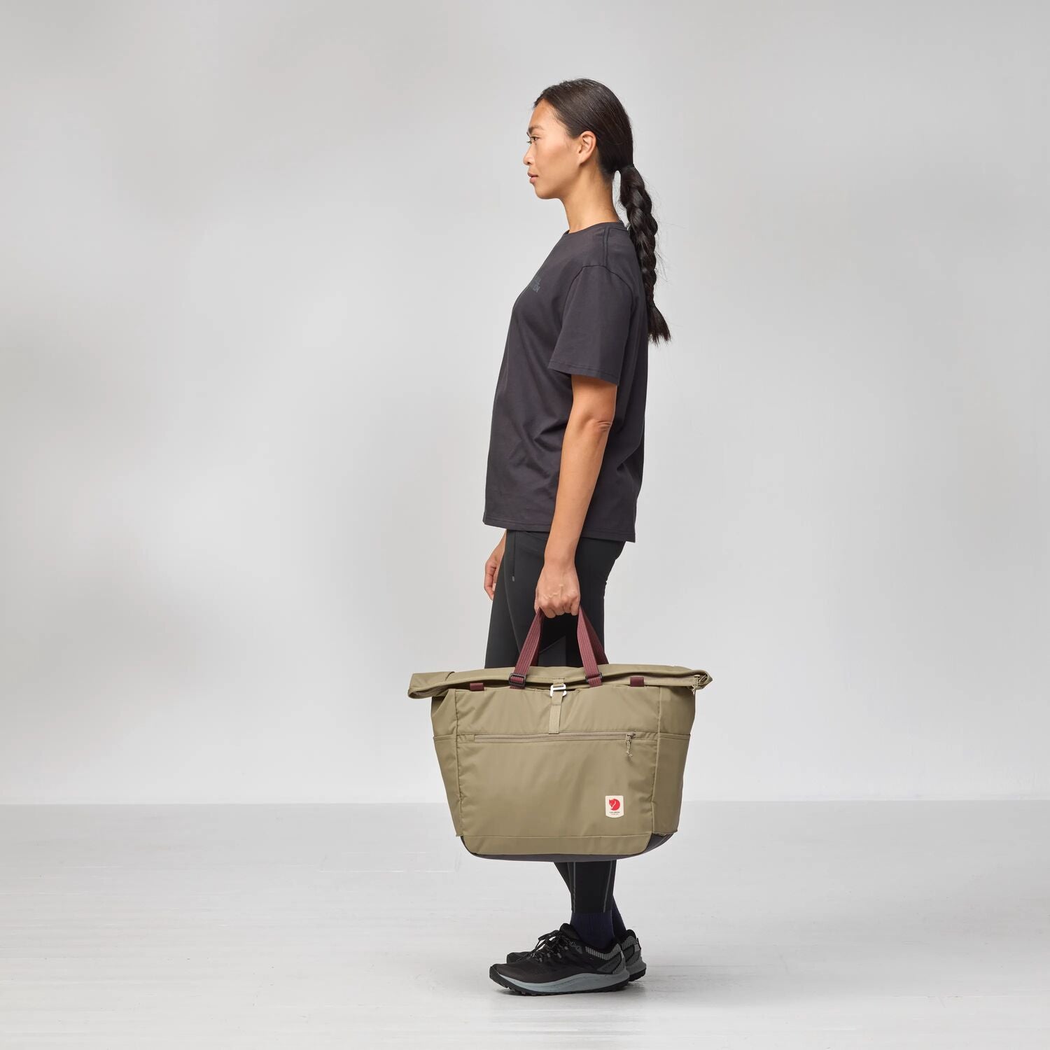 Person holding a beige bag against a white background