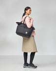Person holding a black bag against a gray background