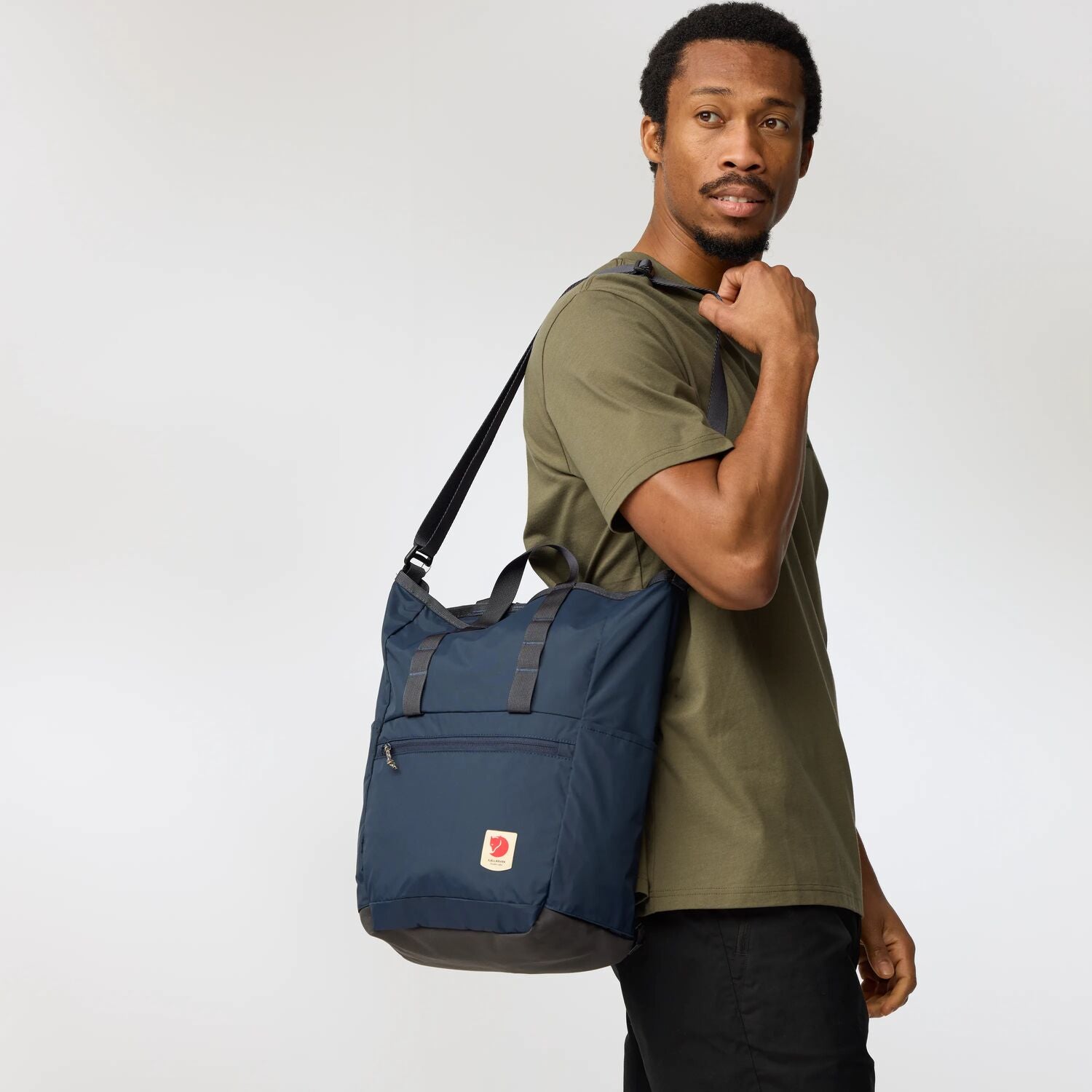 Man holding a navy blue bag against a white background