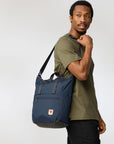 Man holding a navy blue bag against a white background