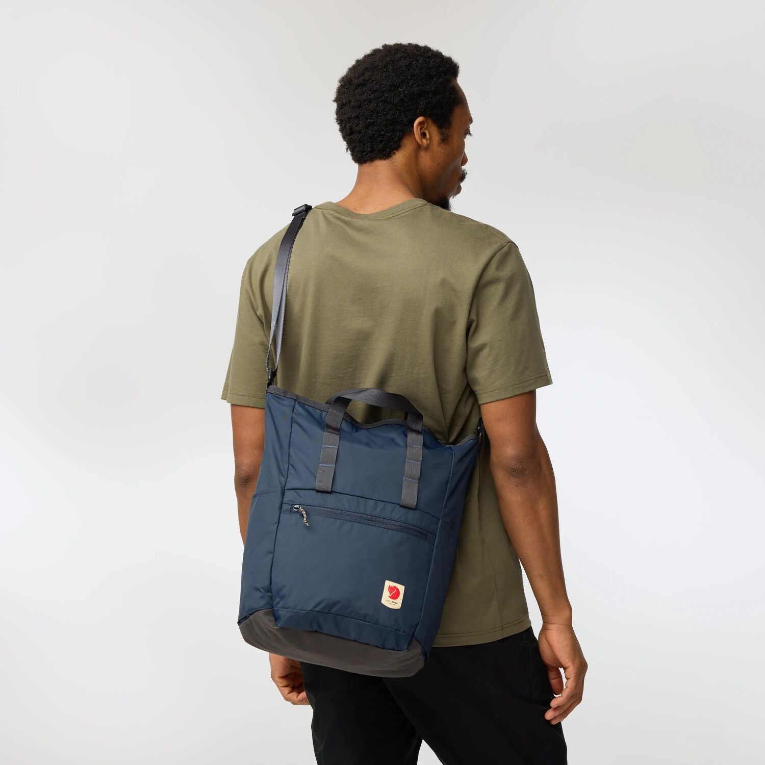 Person wearing a blue backpack totepack on a plain background