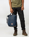 Person holding a navy blue backpack with a white background