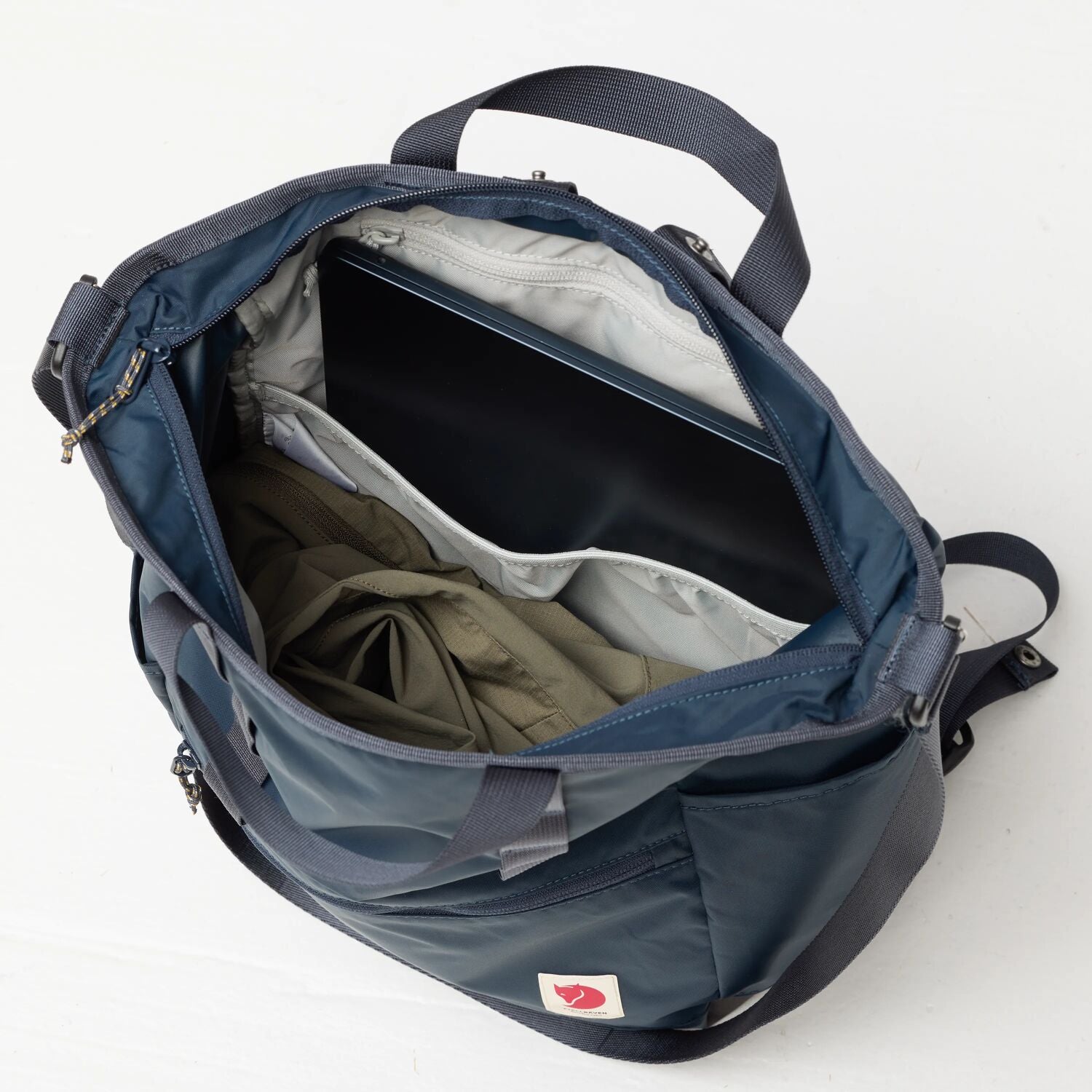 Open blue backpack with items inside on a white background