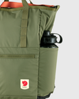 Green backpack with a water bottle in the pocket on a light gray background