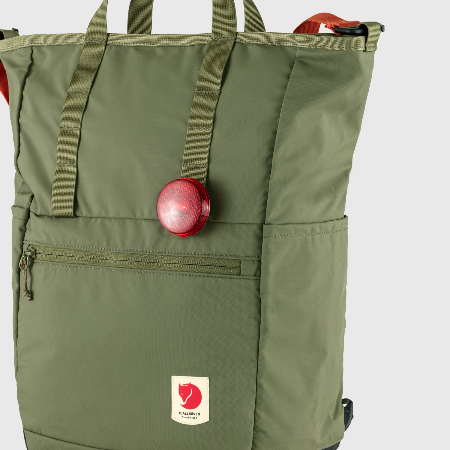 Green backpack with a red light and visible brand logo on a white background