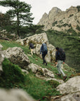 Three hikers with backpacks walking on a rocky mountain trail.