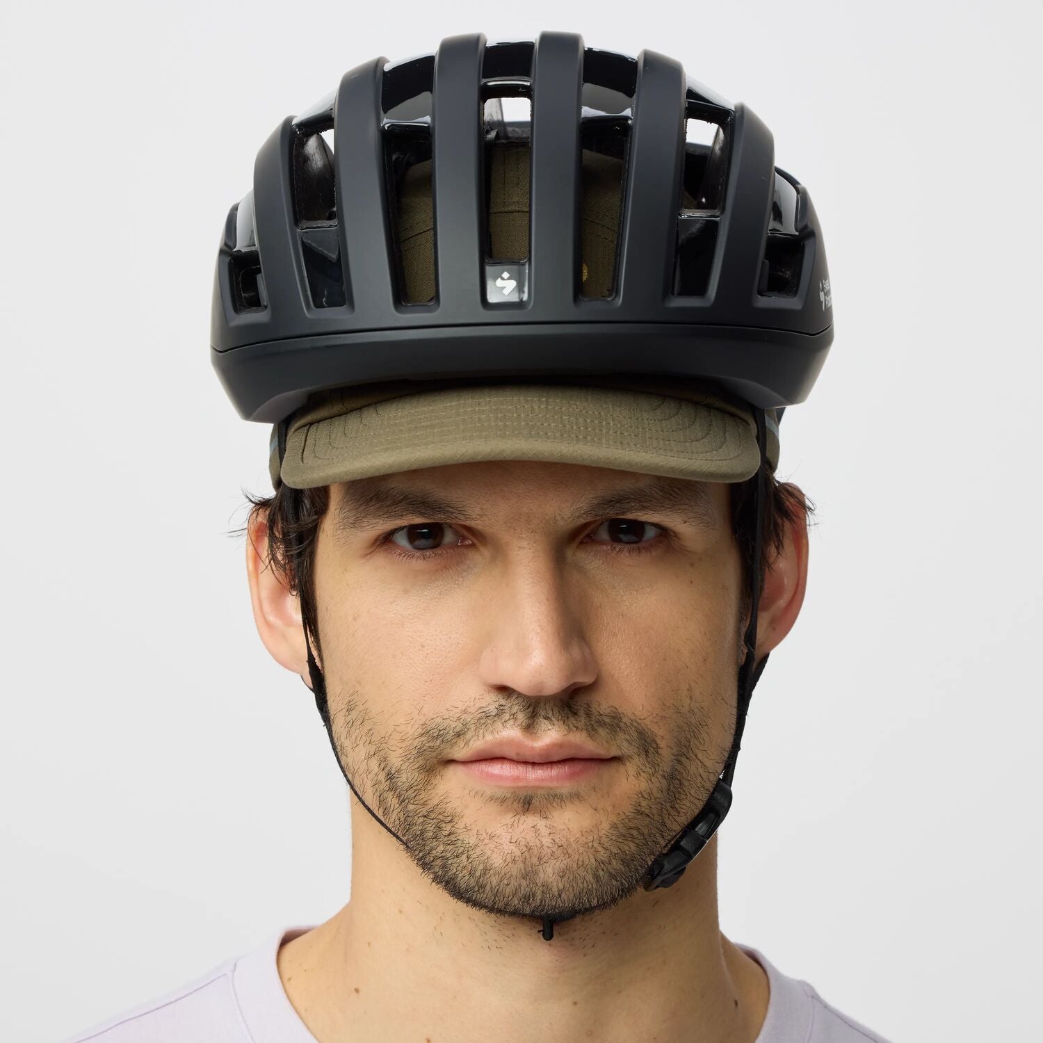 Man wearing a black helmet and green cap on a white background