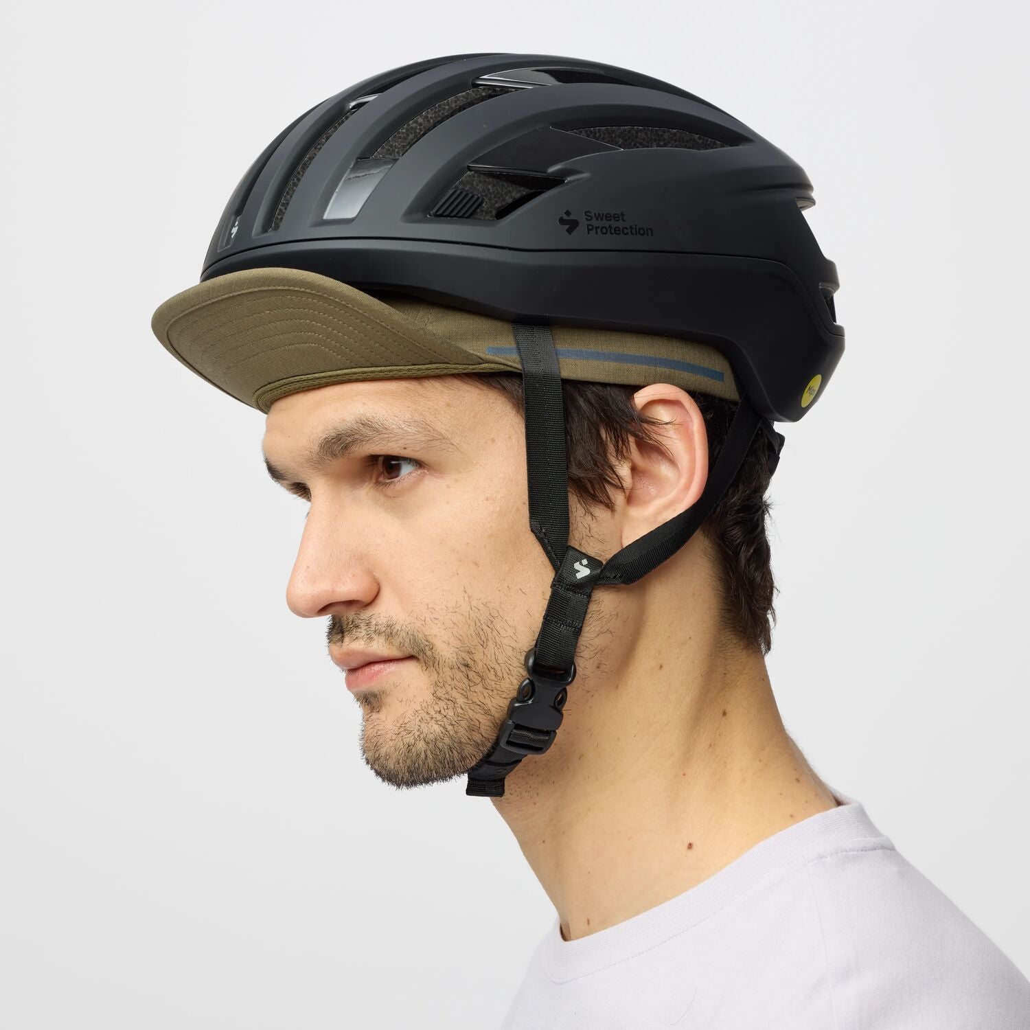 Person wearing a black helmet with a green cap on a white background