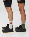 Two pairs of legs wearing black shoes and colorful socks on a white background