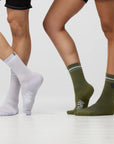 Two pairs of legs wearing white and green socks on a light gray background