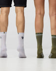 Two pairs of legs wearing white and green socks on a plain background