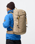 Person wearing a blue jacket and brown backpack on a white background