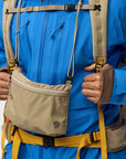 Person wearing a blue jacket with a beige sling bag on a white background