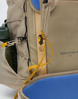Close-up of a beige backpack with blue cushion and water bottle holder.