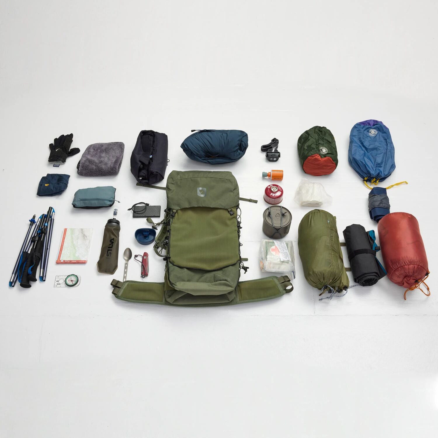 Collection of hiking and camping gear arranged around a green backpack on a white background