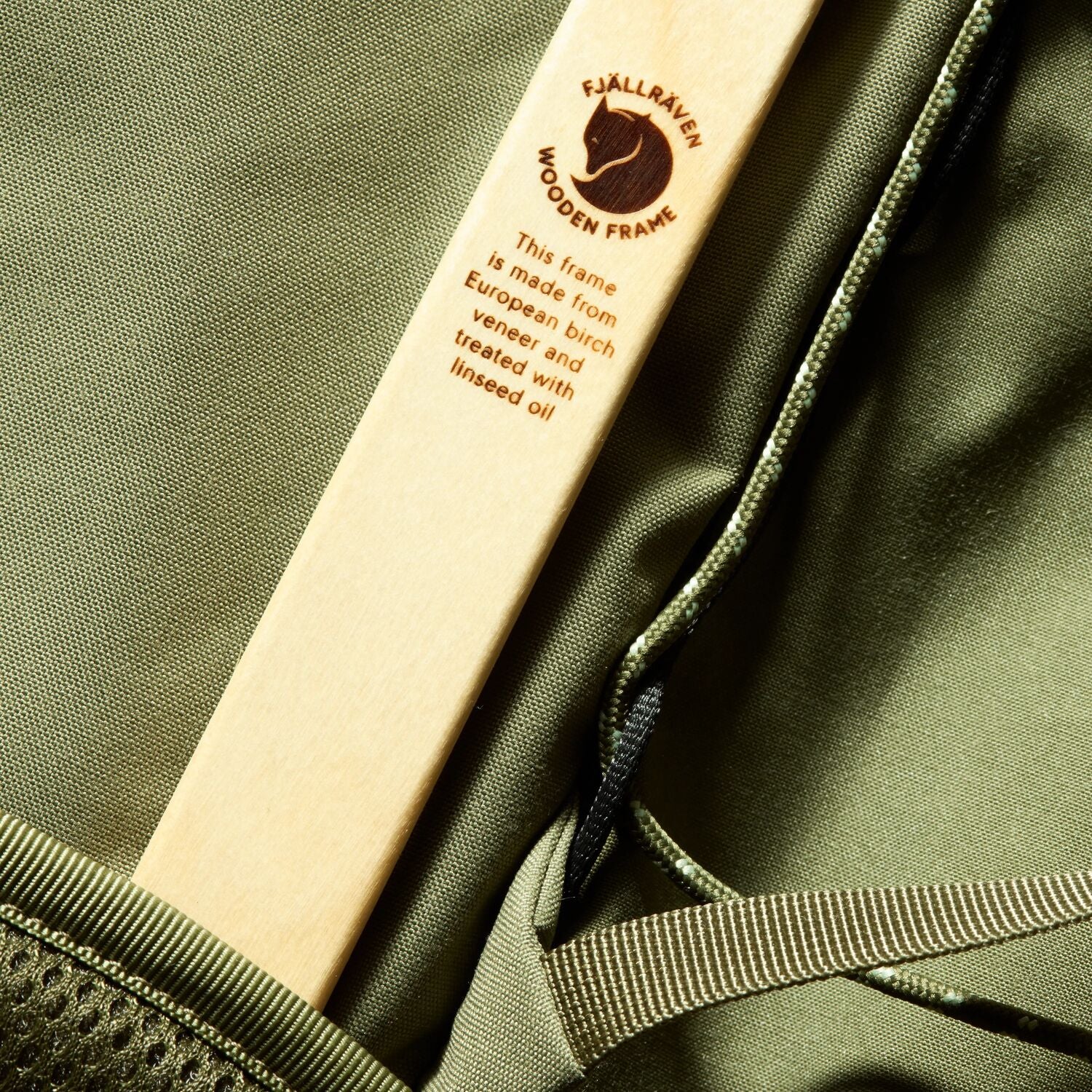 Wooden frame with Fjällräven branding on a green fabric background