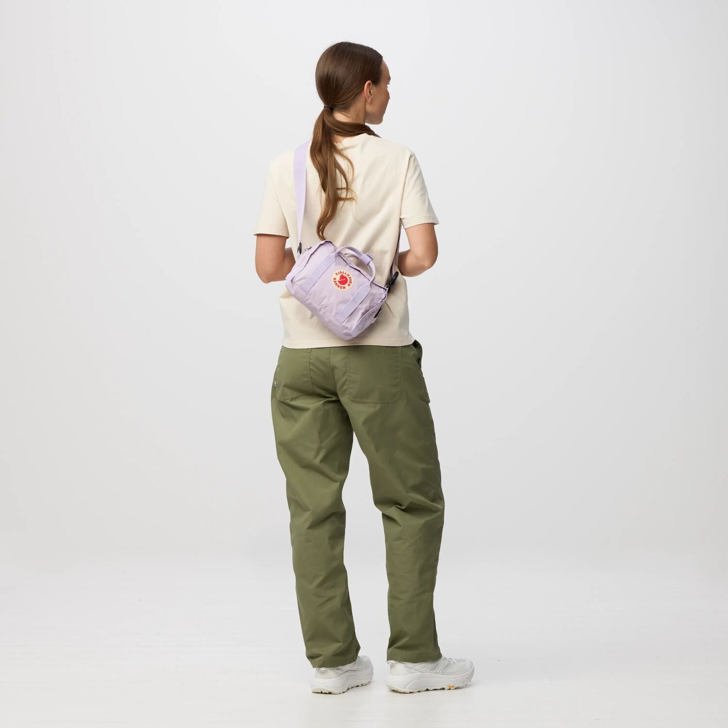 Person wearing a light purple backpack with a visible brand logo on a white background