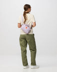 Person wearing a light purple backpack with a visible brand logo on a white background