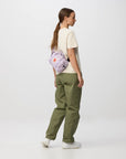 Person wearing green pants and a light-colored shirt with a purple bag on a white background