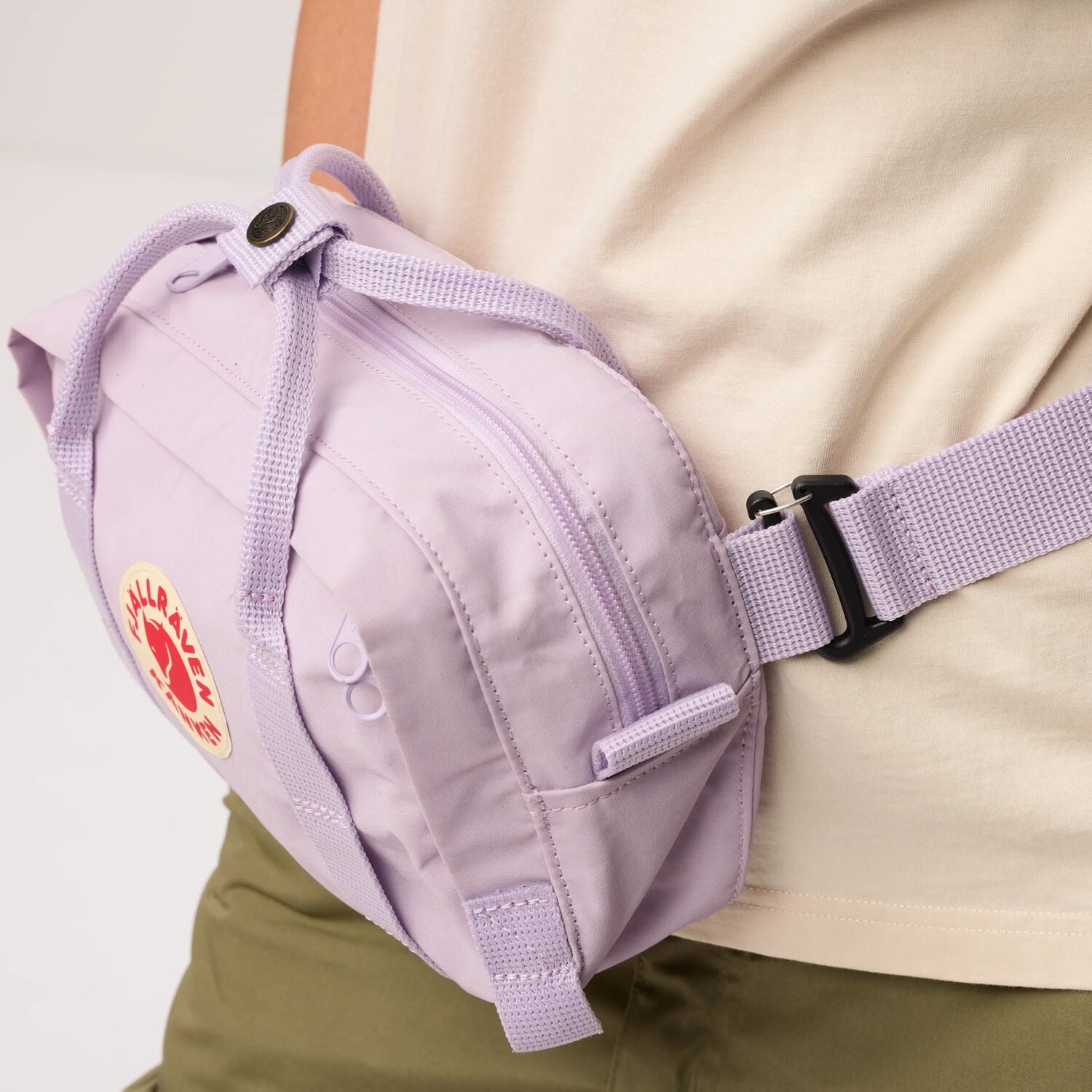 Purple waist bag with a visible brand logo worn by a person on a light background