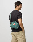 Man wearing a teal backpack on a plain background