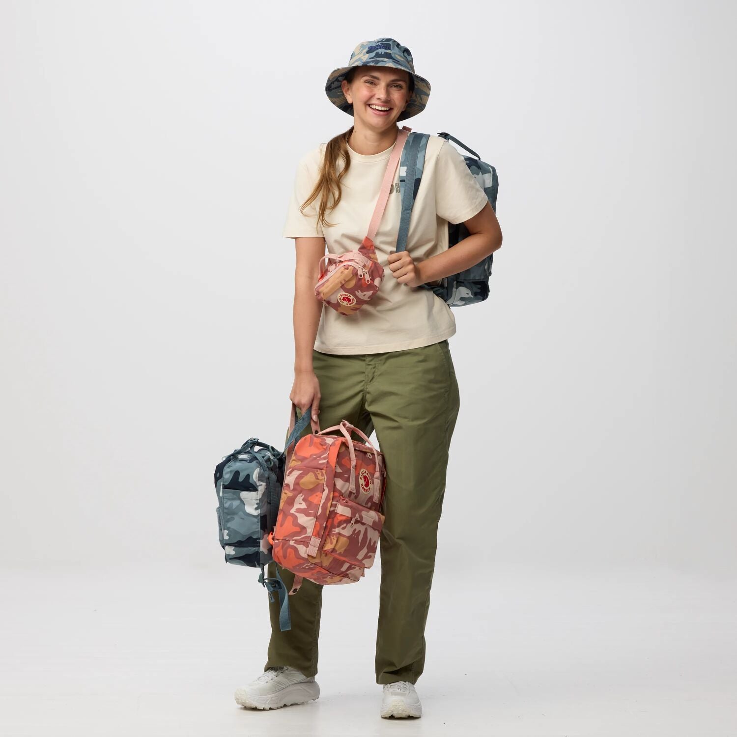 Person holding two backpacks against a white background