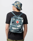 Person wearing a camouflage backpack and bucket hat on a white background