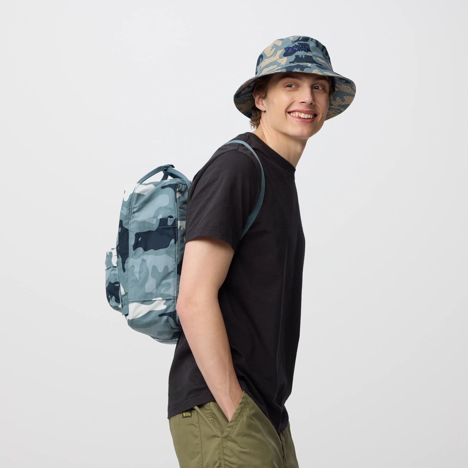 Person wearing a camouflage backpack and hat on a white background