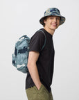 Person wearing a camouflage backpack and hat on a white background