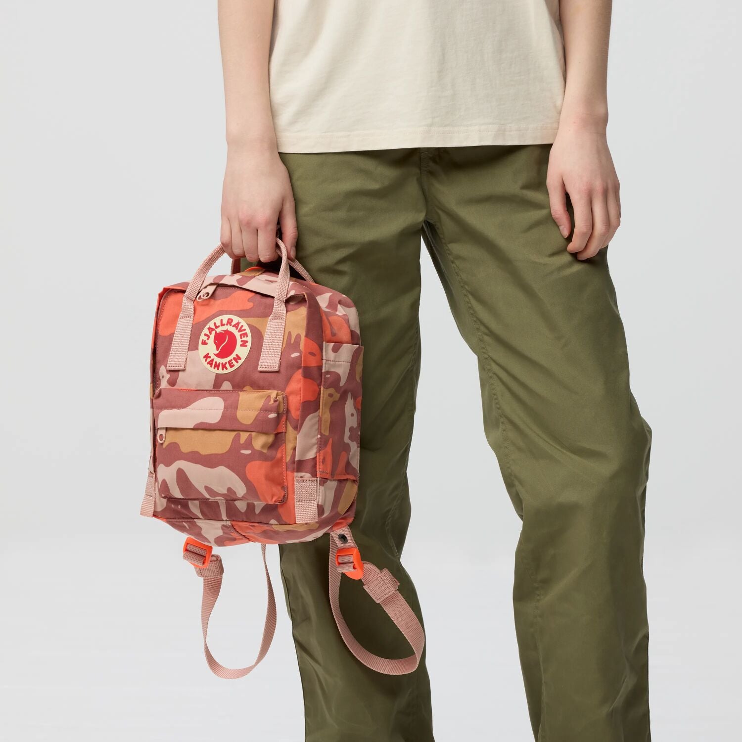 Person holding a camouflage-patterned backpack with a neutral background