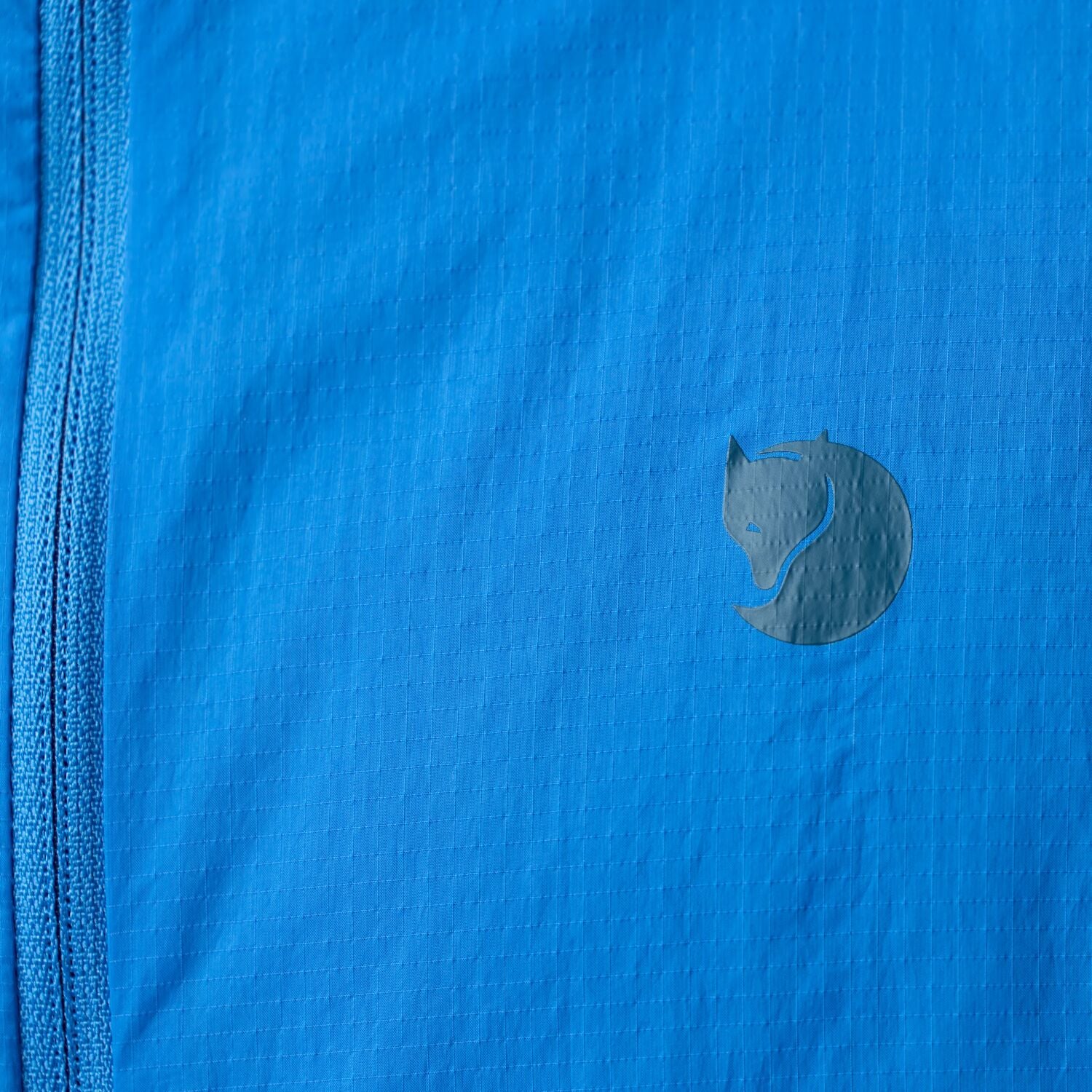 Close-up of a blue fabric with a logo on a jacket