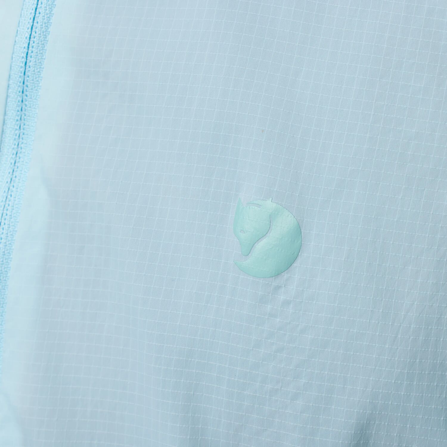 Close-up of a light blue textured fabric with a arctic fox logo.