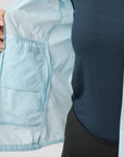 Light blue jacket with a pocket held open by a hand on a light gray background