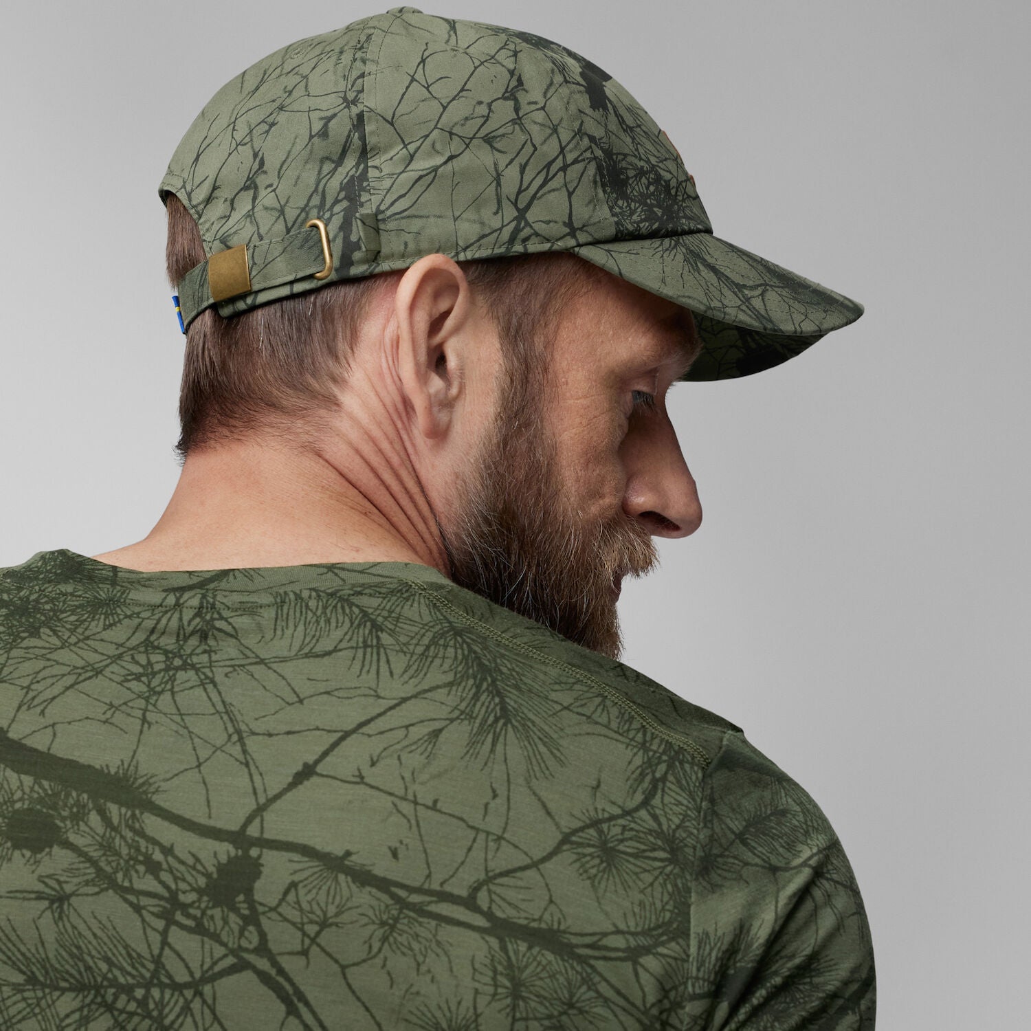 Man wearing a camouflage cap and shirt against a gray background