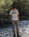 man wearing a fossilround neck t-shirt  standing on pebbled stones