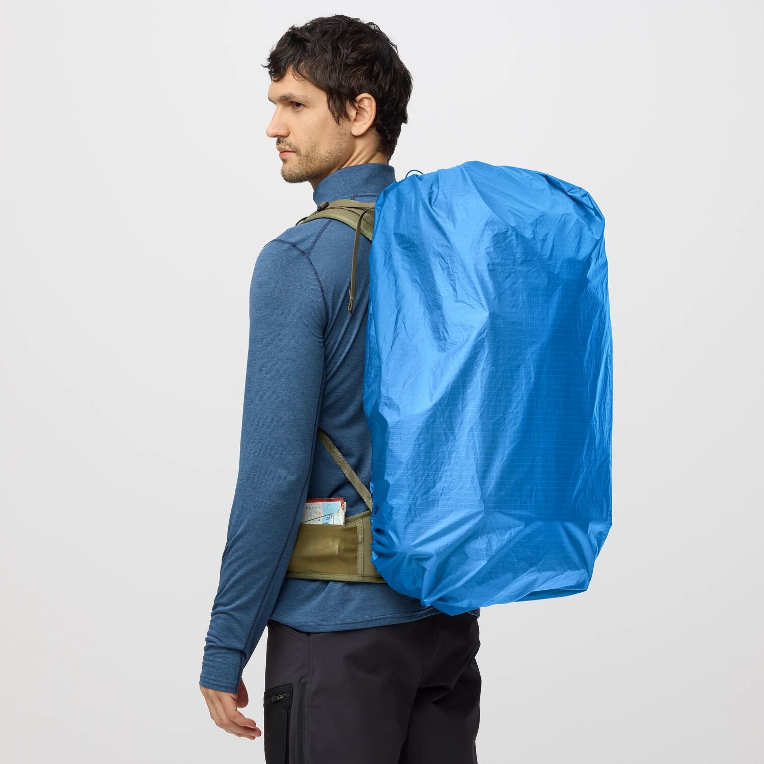 Person wearing a blue backpack cover on a plain background