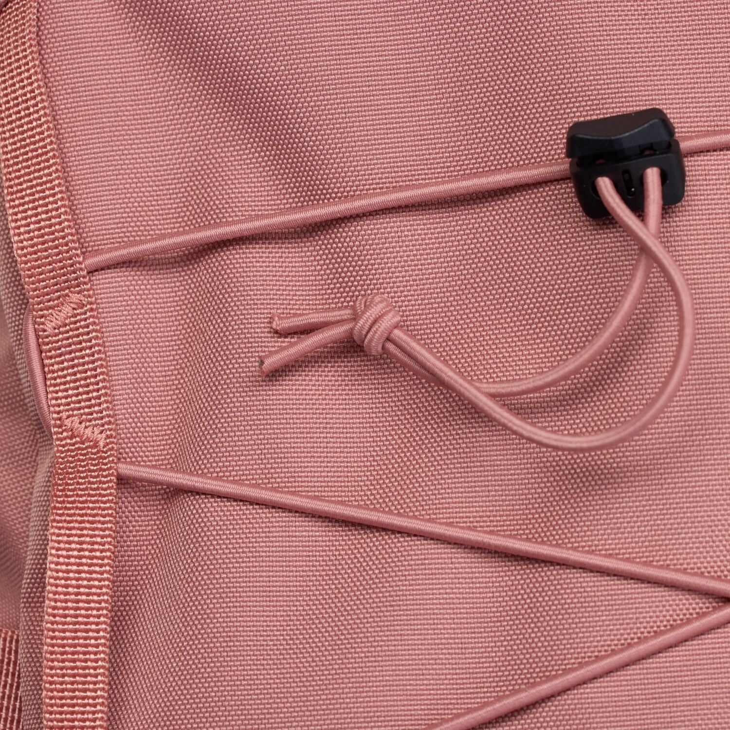 Close-up of a pink backpack with a drawstring and black clip.