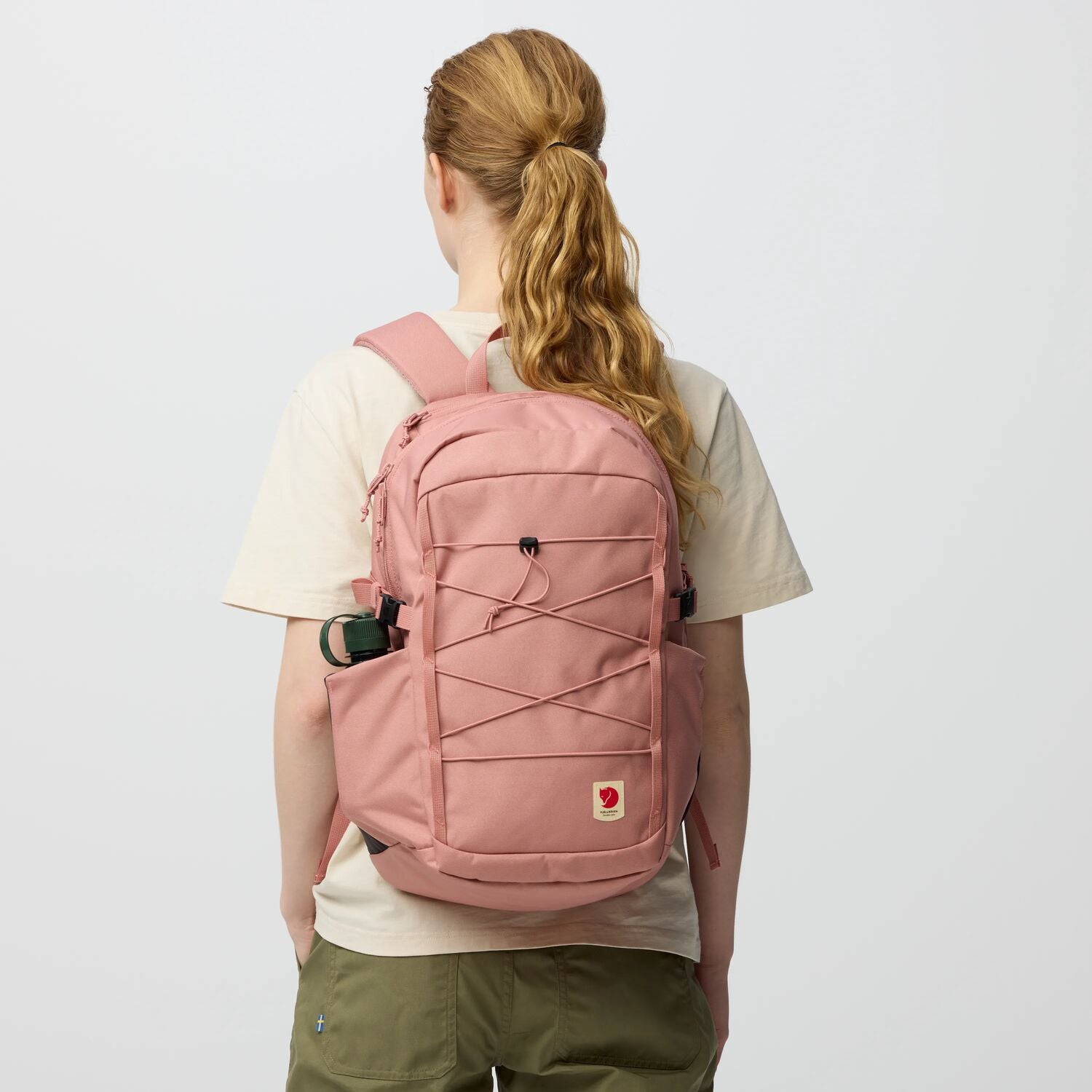 Person wearing a pink backpack on a plain background