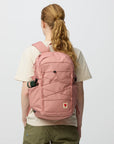 Person wearing a pink backpack on a plain background