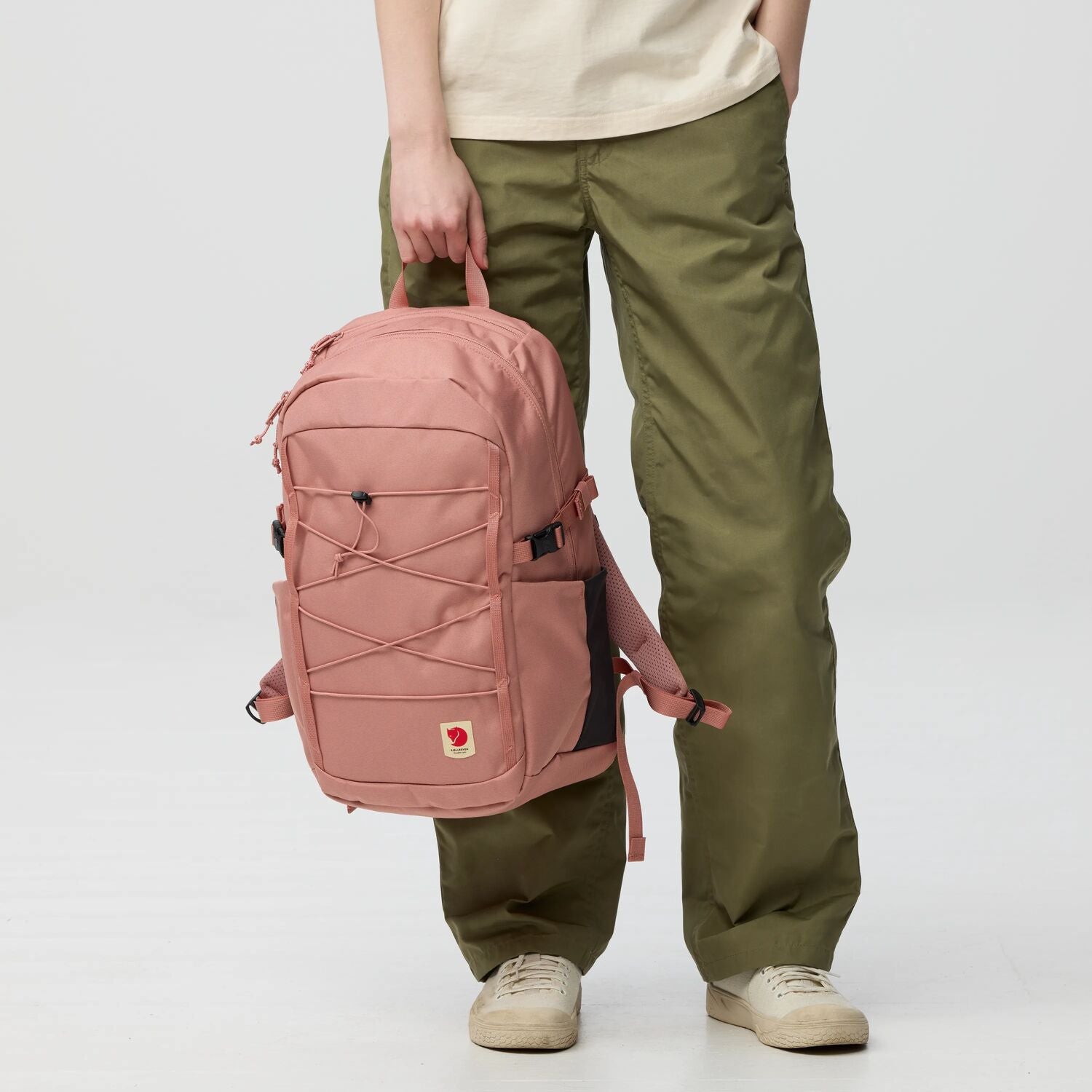 Person holding a pink backpack with a visible Fjällräven logo on a white background