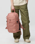 Person holding a pink backpack with a visible Fjällräven logo on a white background