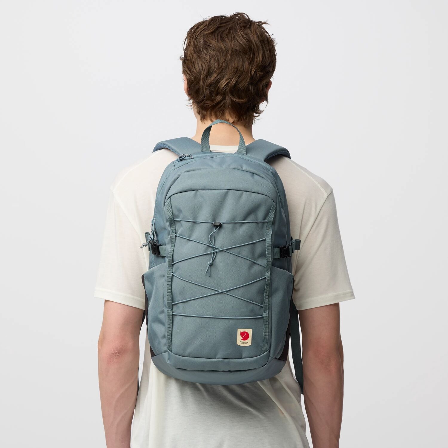 Person wearing a light blue backpack on a plain background