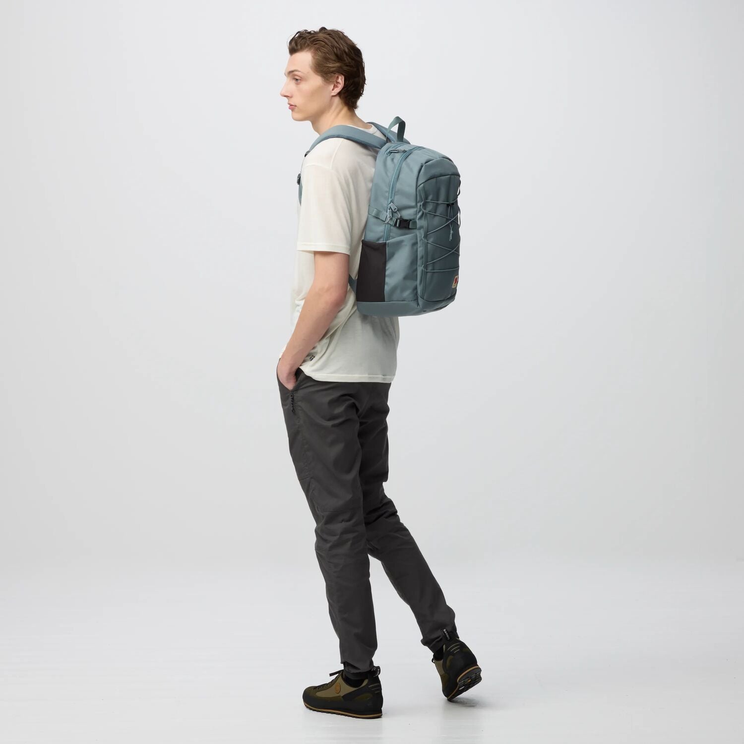 Person wearing a gray backpack on a white background