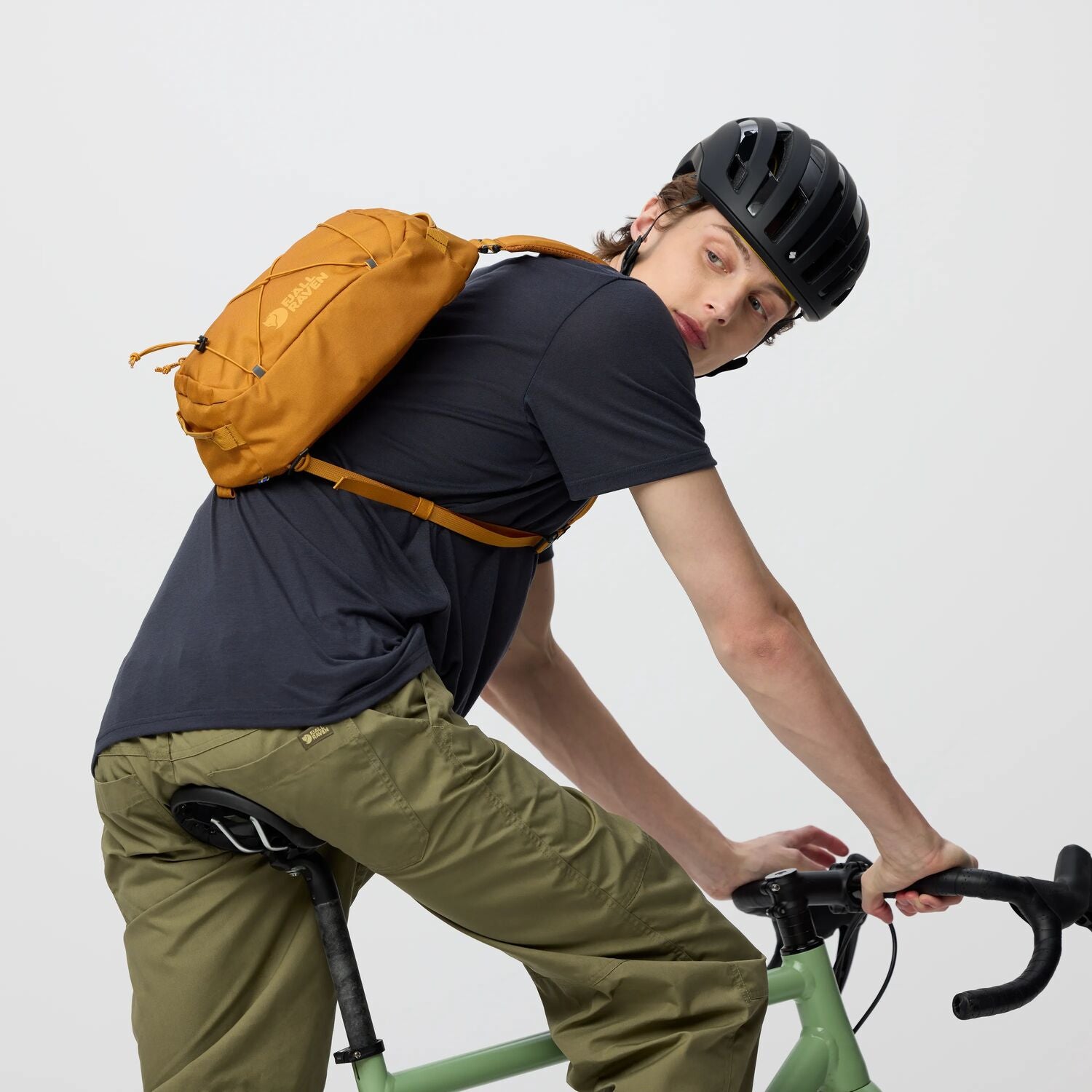 Person riding a bicycle with a yellow backpack on a plain background