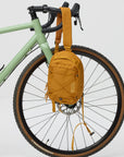 Yellow sling bag attached to a bicycle on a white background