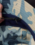 Close-up of a camouflage-patterned fabric with a hand adjusting a black strap.