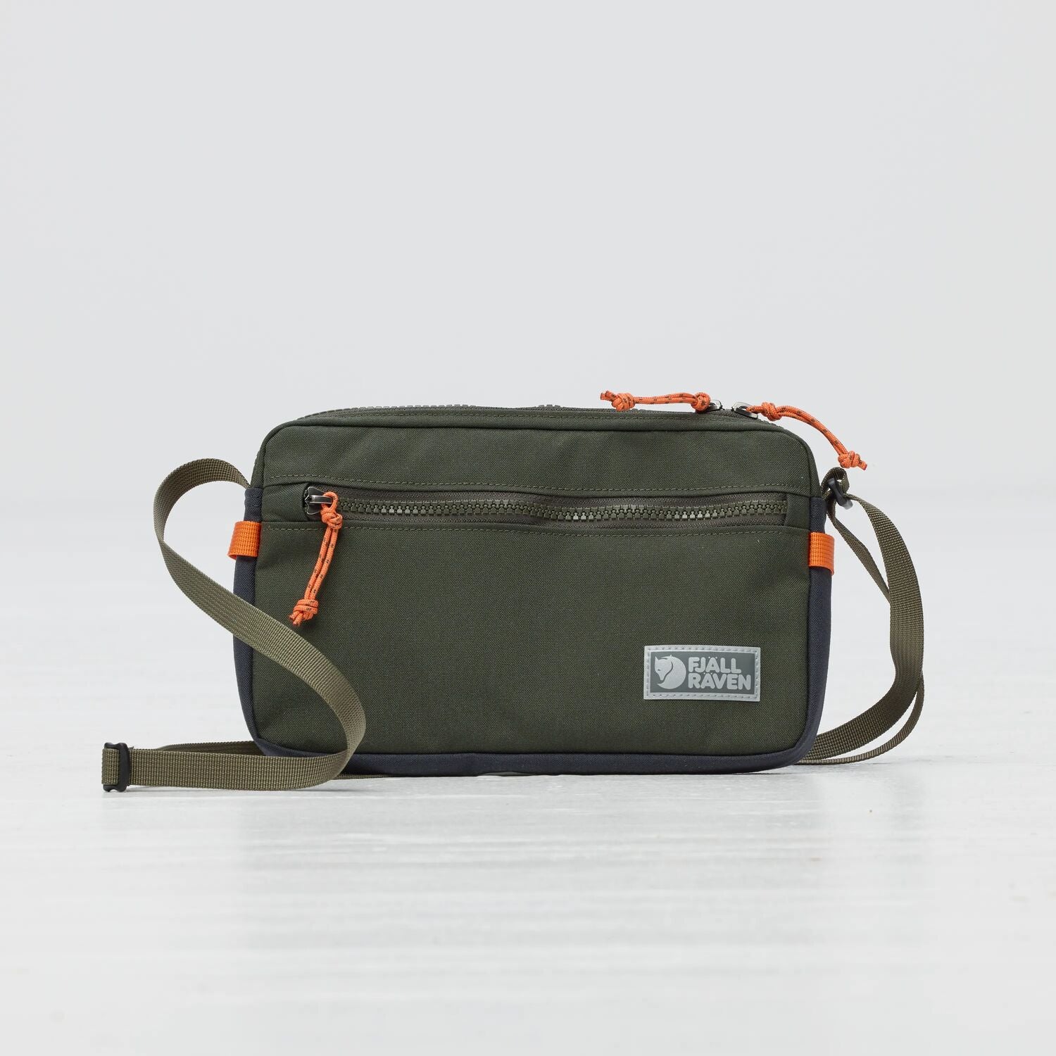 Green crossbody bag with orange accents on a light gray background